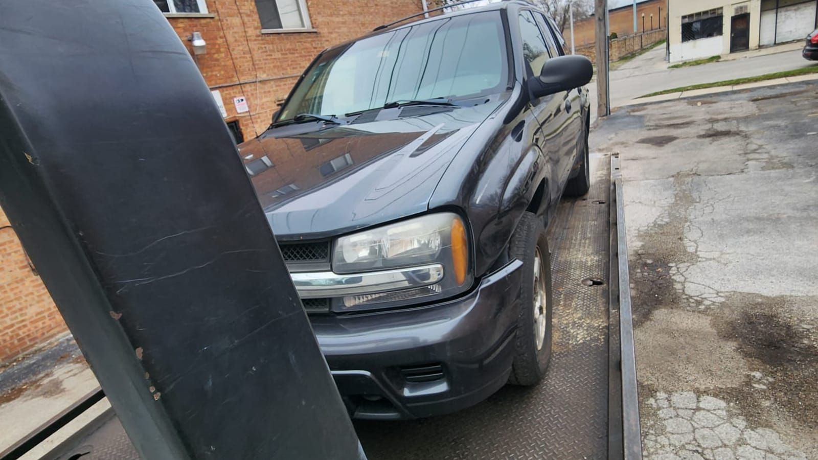 Dark grey SUV on the deck of a flatbed tow truck