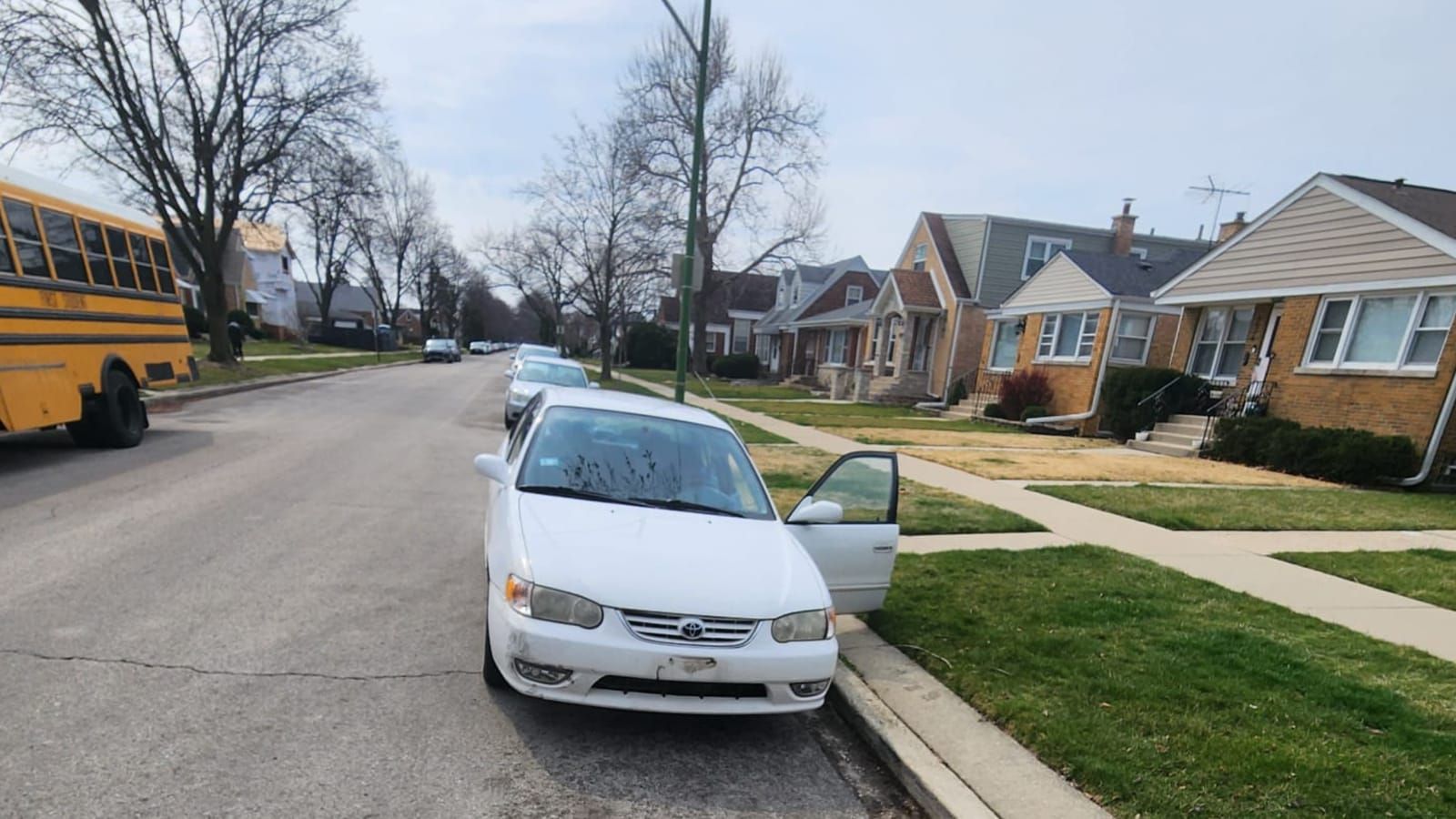White Toyota Corolla parked at the curb with its driver door open